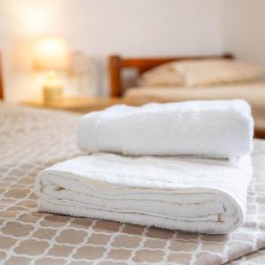 3 toallas están apiladas en la parte superior de una cama en Seaside Retreat for Families and Pets, en Messini