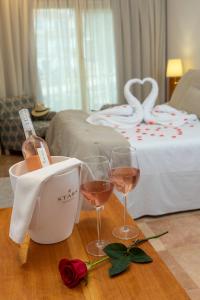 a table with two glasses of wine and a bed at Hotel Spa Porto Cristo in Port de la Selva