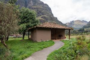Hacienda Hostería Dos Chorreras في كوينكا: مبنى صغير بمسار بجانب جبل