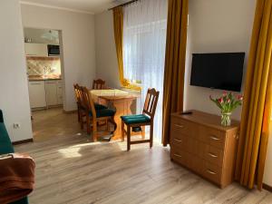 een woonkamer met een televisie en een eettafel bij Baracuda in Dębki