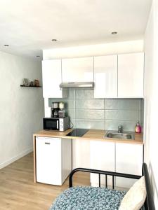 a kitchen with white cabinets and a microwave at Le Nid du Miroir in Martigues