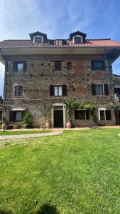 a large brick building with a grass yard in front of it at Cascina Ciosse B&B in Grognardo