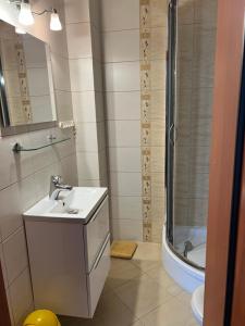 een witte badkamer met een wastafel en een douche bij Baracuda in Dębki