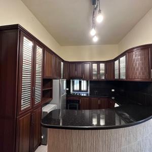 a kitchen with wooden cabinets and a black counter top at Wave Side Old Souk Batroun Guest House in Batroûn