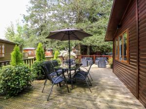 a patio with a table and chairs and an umbrella at Footprints Lodge in Windermere