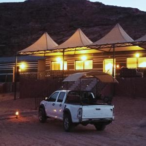 un camion bianco parcheggiato di fronte a una casa di notte di Miral Night Camp a Wadi Rum