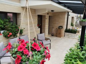a porch with red flowers and a swing at Family Boutique Residence-Free parking in Veliko Tŭrnovo