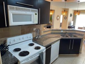 a kitchen with a white stove and a microwave at Corona del Mar By Rocky Host in Puerto Peñasco
