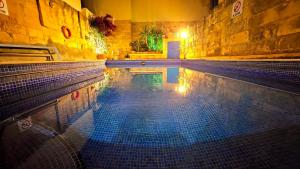 uma piscina com piso em azulejo num edifício em Ta Katrin 3 Bedroom Farm House em Xaghra