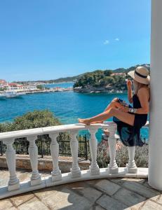 a woman sitting on a railing looking at the water at ClubOrsa Ourania's Mansion in Skiathos Town