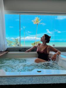 a woman in a bathtub with a view of the ocean at Kastel Jampa Hotel in João Pessoa