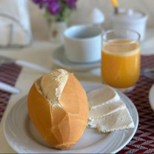 um prato com uma sanduíche e um pouco de pão e sumo de laranja em Hospedagem Platô em Monte Verde