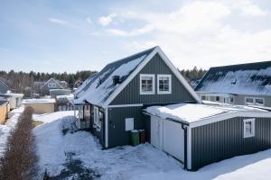 a green house with snow on the roof at Guestly Homes - Spacious 5BR Villa with Sauna in Södra Sunderbyn