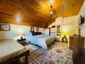 um quarto com uma cama grande e um tecto de madeira em Hospedagem Platô em Monte Verde