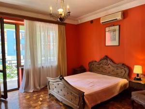 een slaapkamer met oranje muren en een bed en een raam bij Guesthouse Parnavaz Mepe in Batoemi