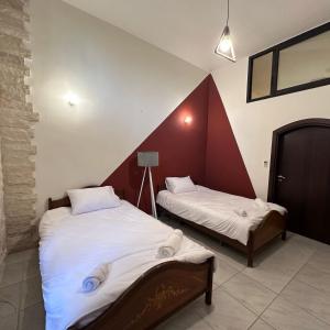 two beds in a room with red and white walls at Wave Side Old Souk Batroun Guest House in Batroûn +4 photos
