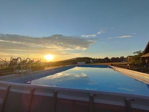 a large swimming pool with the sunset in the background at Apartamenty przy szlaku in Krajno Pierwsze