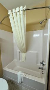 オークレアにあるQuality Inn & Suitesのバスルーム(白いバスタブ、シャワーカーテン付)