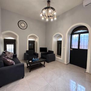 a living room with a couch and a clock on the wall at Wave Side Old Souk Batroun Guest House in Batroûn