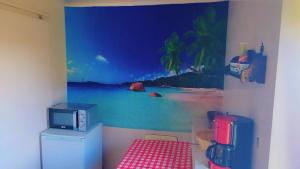 ein Zimmer mit einer Wand, an der ein Gemälde eines Strandes prangt in der Unterkunft Lavignegîte in Bugeat