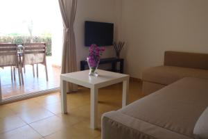 sala de estar con sofá y mesa con flores. en Cala Vigliena Il Sole Negli Occhi en Punta Braccetto