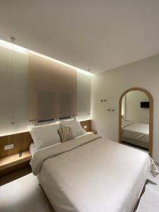 a bedroom with a large white bed and a mirror at Venice Studios & Apartments in Stavros