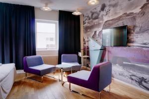 Comfort Hotel Jönköping في يونيشوبينغ: غرفة بها كرسيين أرجوانيين وتلفزيون