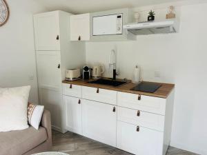 a kitchen with white cabinets and a sink at Equi-Lodge Jacuzzi au coeur des chevaux & de la nature proche Disney in La Houssaye-en-Brie