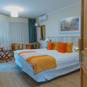 Habitación de hotel con cama grande con almohadas de color naranja en Termas El Corazon, en San Esteban