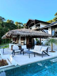 un complexe hôtelier avec piscine et terrasse aménagée avec canapés et toit de chaume dans l'établissement Casa Ventanas Matapalo Luxe Villa, à Cabo Matapalo 7 autres photos