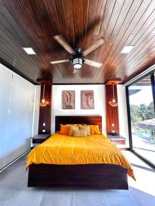 - une chambre avec un lit jaune et un plafond en bois dans l'établissement Casa Ventanas Matapalo Luxe Villa, à Cabo Matapalo