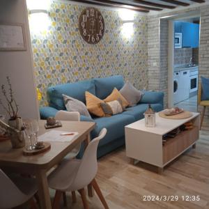 ein Wohnzimmer mit einem blauen Sofa und einem Tisch in der Unterkunft Apartamento Turístico El Empedrado de M&G in Colmenar de Oreja