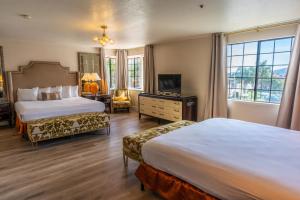 Cette chambre comprend deux lits et une télévision. dans l'établissement Sands Inn & Suites, à San Luis Obispo