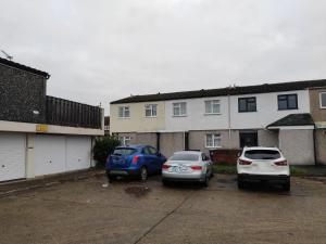 two cars parked in a parking lot in front of a building at Elegant 3-Bedroom Home, sleeps up to 5 guest. in South Ockendon