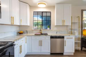 Biała kuchnia z białymi szafkami i oknem w obiekcie Sands Inn & Suites w mieście San Luis Obispo