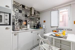 a white kitchen with a table and a chair at Chalé do Vale in Pinhal Novo