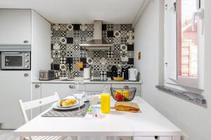 a white kitchen with a table with a plate of food at Chalé do Vale in Pinhal Novo