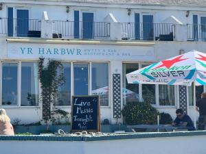 a restaurant with an umbrella in front of a building at The Harbour Bar & Bistro in Cemaes Bay