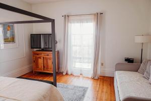 a bedroom with a bed and a tv and a couch at The Montague Rose Inn & Cafe in Saint Andrews
