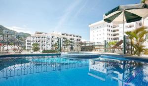 une piscine avec un parasol et un bâtiment dans l'établissement Vallarta Jr Suites, à Puerto Vallarta