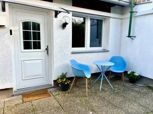 dwa niebieskie krzesła i stół przed drzwiami w obiekcie Mini Apartment mit Garten und Küche w mieście Ilbenstadt