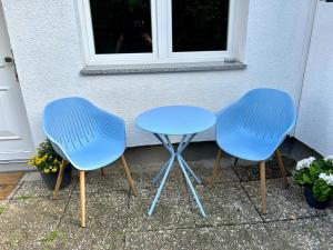 two blue chairs and a table in front of a house at Mini Apartment mit Garten und Küche in Ilbenstadt +5 photos