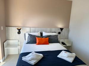 um quarto com uma cama grande com travesseiros laranja em Flat 428 no centro de Cabo Frio a 700m da praia em Cabo Frio mais 28 fotografias