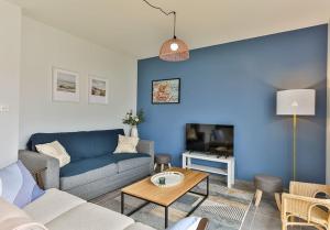 een woonkamer met een blauwe bank en een tafel bij Serpentine, à 5mn des plages in Saint-Hilaire-de-Riez