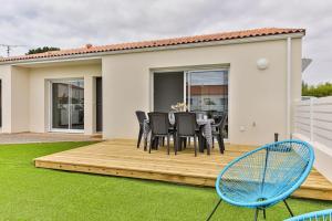 een houten terras met een tafel en stoelen erop bij Serpentine, à 5mn des plages in Saint-Hilaire-de-Riez