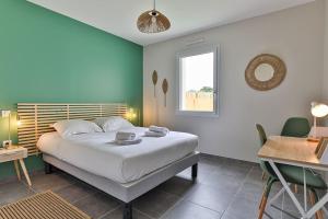 een slaapkamer met een bed, een bureau en een raam bij Serpentine, à 5mn des plages in Saint-Hilaire-de-Riez