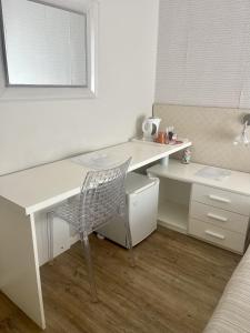 escritorio blanco con silla y espejo en Hotel Villa Rosa en Porto Azzurro