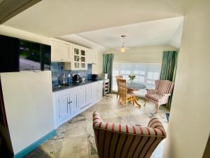 a kitchen with white cabinets and a table and chairs at Lynwood House Self Contained Studio in Tregoney