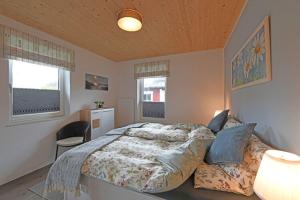 a bedroom with a large bed and two windows at Ferienhaus in Schlagsdorf auf Fehmarn in Schlagsdorf