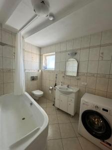 a bathroom with a tub sink and a washing machine at Wileńska Pokoje in Słupsk